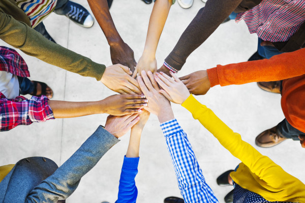 Zusammenarbeit, viele Menschen haben sternförmig ihre Hände übereinandergelegt , bunt und vielfältig.